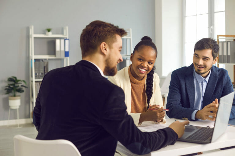 bank manager in the office consults a caucasian man and his african american wife.