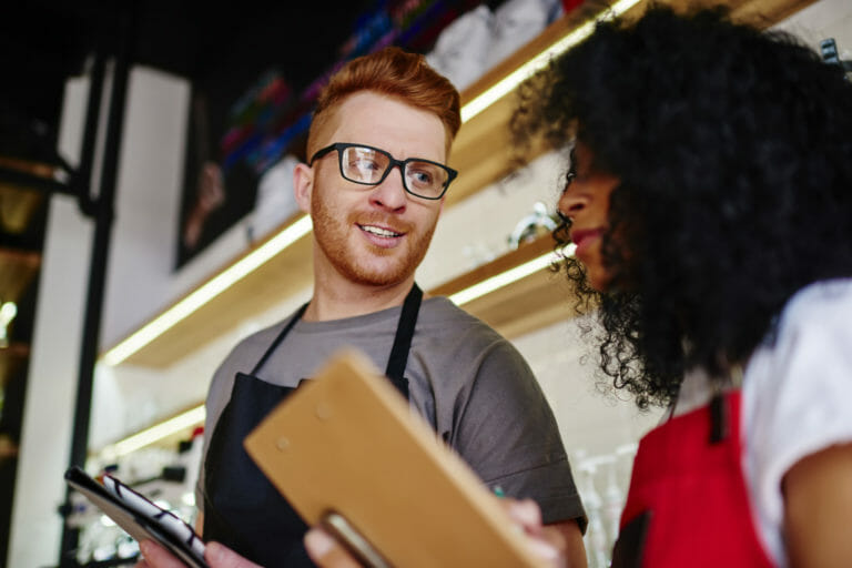 caucasian waiter and african american waitress in red aprons com