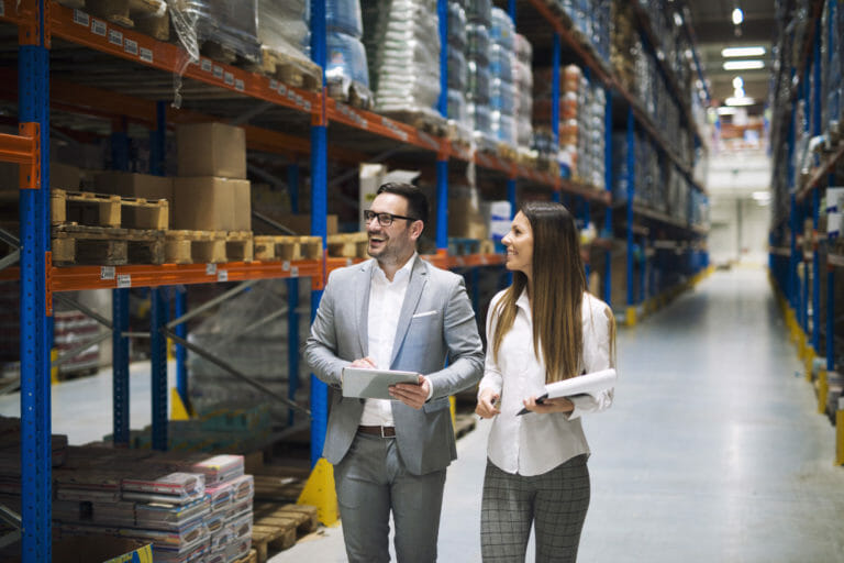two successful business people walking through large warehouse c