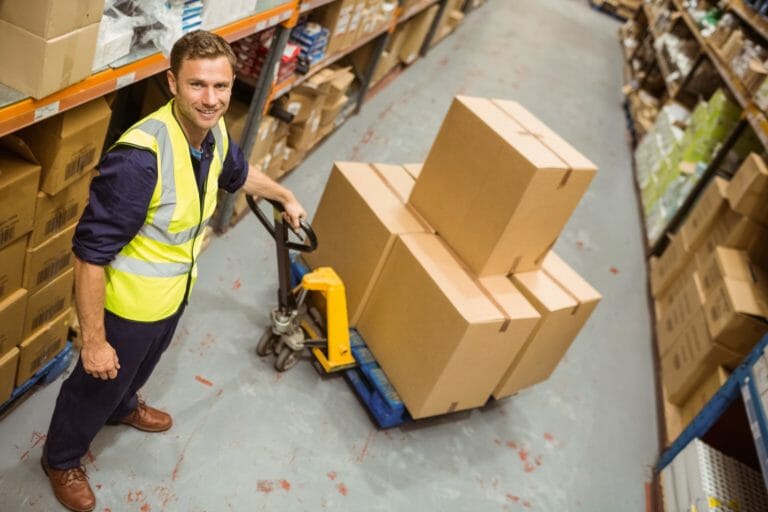 worker with trolley of boxes smiling at camera