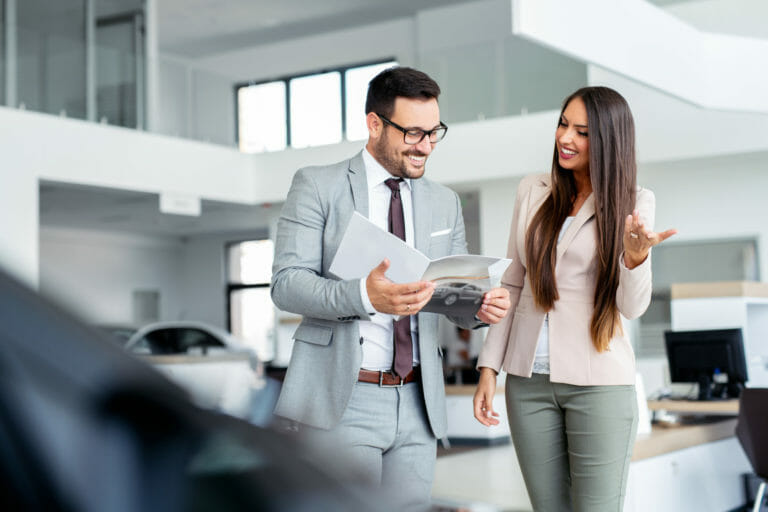 beautiful saleswoman presenting cars to a customer